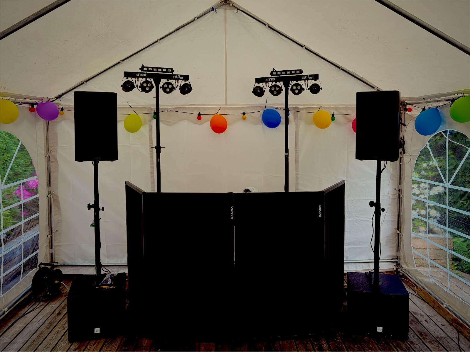 Felix' DJ-setup i et festtelt: to højttalere på stativ, to subwoofere, to lysbarer og en sort DJ-facade